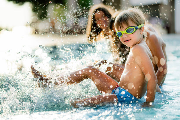 istock Playful kids having fun while splashing water in the swimming pool 1332275431