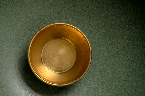 A brown bowl with a gold rim sits on a white table