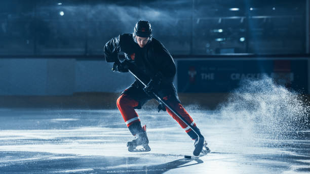 istock Ice Hockey Rink Arena: Professional Player Training Alone. Skates, Practices Shooting, Hitting, Stricking the Puck with Hockey Sticks. Determined Athlete with Desire to Win, Be Champion. 1332278051