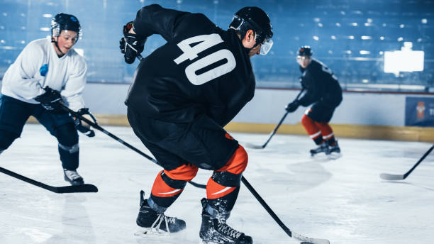 istock Ice Hockey Rink Arena: Professional Defender Player Attacks, Pushing Attacker Aggressively, Trying to take the Puck. Competitive Intense Game with Skill, Speed, Energy, Power. 1332278052