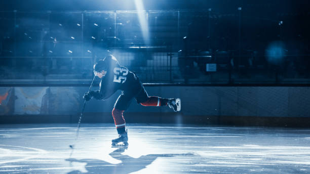 istock Ice Hockey Rink Arena: Professional Player Training Alone. Skates, Practices Shooting, Hitting, Stricking the Puck with Hockey Sticks. Determined Athlete with Desire to Win, Be Champion. 1332278072