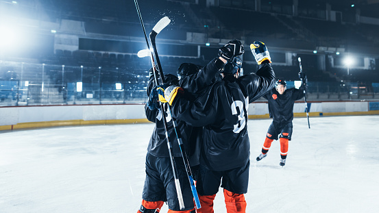 Ice Hockey Rink Arena: Forward Player Hit The Puck and Scored a Goal. Professional Hockey Team Celebrates Victory, Embrace Each Other. Tension and Emotional Sport Moment.