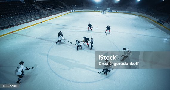 istock Aerial Ice Hockey Rink Arena Game Start: Two Players Brutal Face off, Referee Drops the Puck, Leading with Masterful Dribble Player Scores Goal when Goalie Misses the Puck. Drone High Angle Shot 1332278111