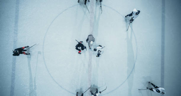 inizio partita arena pista di hockey su ghiaccio top view: due giocatori a faccia in giù, bastoni pronti, arbitro pronto a far cadere il disco. gioco intenso ampio di competizione. colpo drone aereo - hockey foto e immagini stock