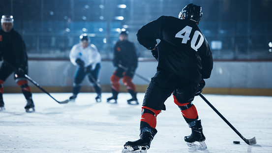 Ice Hockey Rink Arena: Professional Forward Player Breaks Defense, Hitting Puck with Stick to Score a Goal. Game Near Gate or Goal. Important and Tension Moment in Sport Full of Emotions.