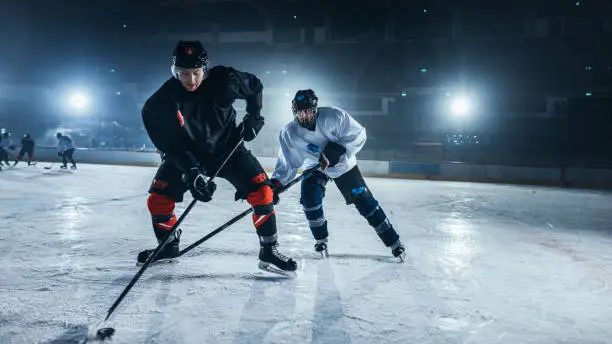 Photo of Ice Hockey Rink Arena: Young Players Training, Learning Stick and Puck Handling. Athletes Learn how to Dribble, Attack, Defend, Protect, Possesion, Drive the Puck.