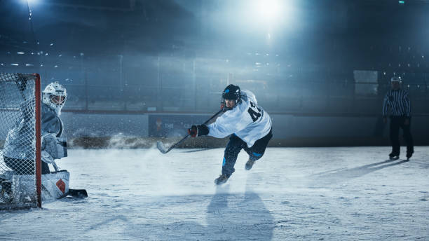 pista de hockey sobre hielo arena: el portero está listo para defender la puntuación contra el jugador delantero que dispara puck con palo. delantero contra portero uno contra uno. momento de tensión en el deporte lleno de emociones. - slap shot fotografías e imágenes de stock