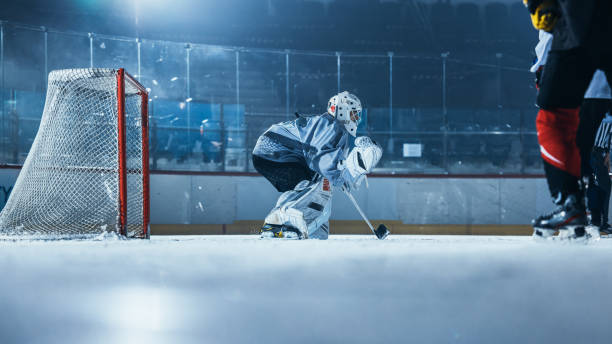 pista de hockey sobre hielo arena: el portero está listo para defender la puntuación contra el jugador delantero que dispara puck con palo. delantero contra portero. momento de tensión en el deporte lleno de emociones. - slap shot fotografías e imágenes de stock