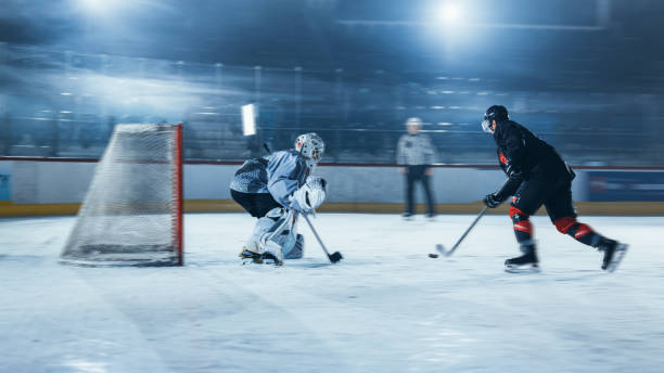 pista de hockey sobre hielo arena: el portero está listo para defender la puntuación contra el jugador delantero que dispara puck con palo. delantero contra portero uno contra uno. momento de tensión con movimiento borroso. - slap shot fotografías e imágenes de stock