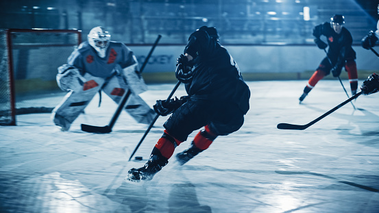 Ice Hockey Arena: Professional Forward Player Breaks Defense, Prepairing to Shot Puck with Stick to Score Goal. Two Competitive Teams Play Intense Game.