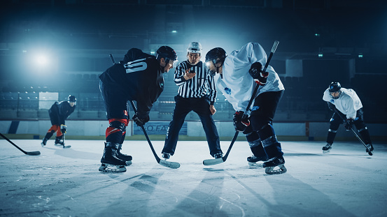 Ice Hockey Rink Arena Game Start: Two Players Brutal Face off, Sticks Ready, Referee is Going to Drop the Puck, Athletes Ready to Fight. Intense Game Wide of Energy Competition, Speed.