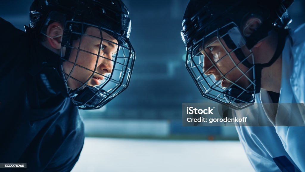 Ice Hockey Rink Arena Game Start: Two Professional Players Aggressive Face off, Sticks Ready. Intense Competitive Game Wide of Brutal Energy, Speed, Power, Professionalism. Close-up Portrait Shot Hockey Stock Photo