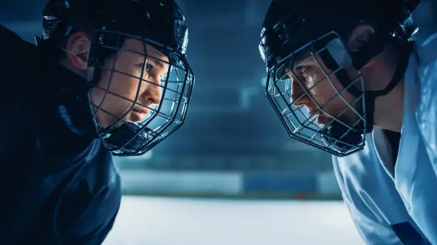 Photo of Ice Hockey Rink Arena Game Start: Two Professional Players Aggressive Face off, Sticks Ready. Intense Competitive Game Wide of Brutal Energy, Speed, Power, Professionalism. Close-up Portrait Shot