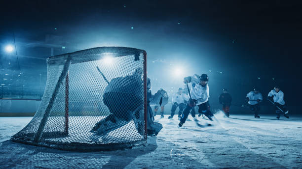 pista de hockey sobre hielo arena: portero contra el jugador delantero que hace slapshot, tiros puck con palo y puntuaciones de gol. delantero contra portero. - slap shot fotografías e imágenes de stock