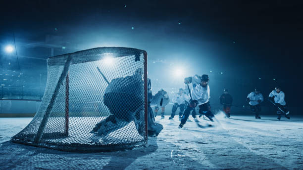 ice hockey rink arena: вратарь против нападающего, который делает удары, удары шайбой клюшкой и забивает гол. нападающий против вратаря. - slap shot стоковые фото и изображения