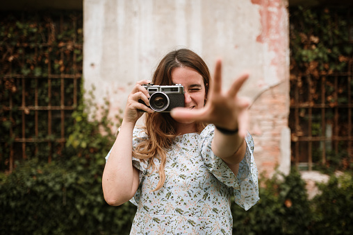A young woman in an abandoned building taking photos with a vintage camera