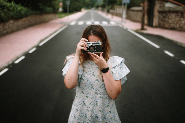 istock Young woman taking a picture with a retro camera 1332279072