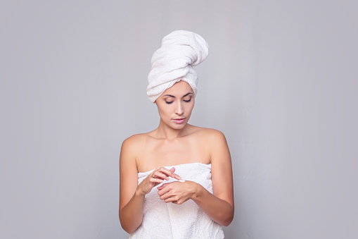 Woman young adult after the shower in a towel fresh uses the funds to care for the skin on an isolated background
