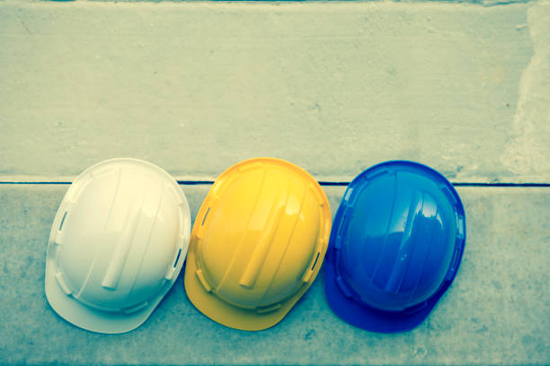 istock Safety helmet Blue, Yellow, White On the concrete wall,Hats for engineering and construction hang on the cement wall. 1332280436