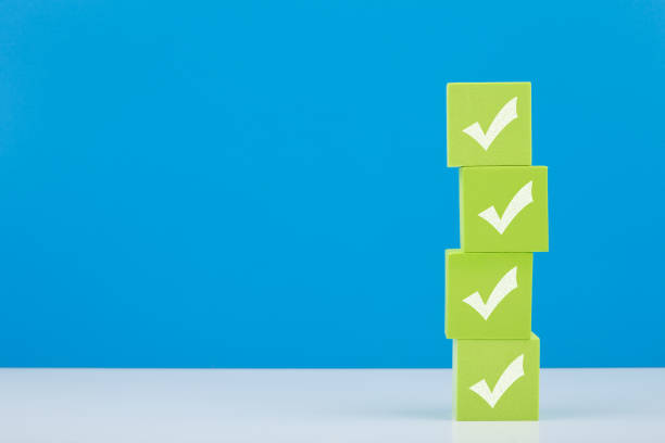 istock Checkmarks on four light green blocks on white table against blue background with copy space 1332282008