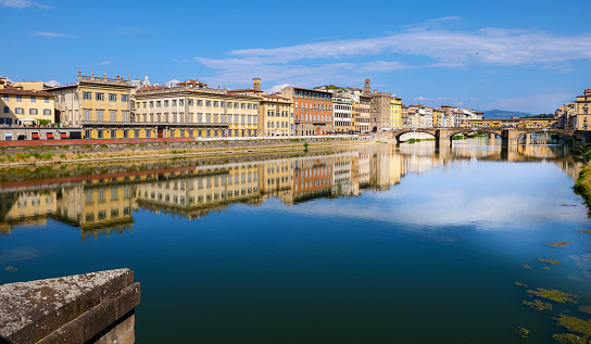 A beautiful and detailed skyline of Florence reflected on the Arno river with the Santa Trinita bridge and the Ponte Vecchio bridge in the historic heart of Renaissance capital, in Tuscany. The district surrounding the Arno is undoubtedly one of the most iconic in Florence, with the presence of important noble palaces, Renaissance churches, artisan and goldsmith shops, refined hotels and some of the most important museums in the world. In background the Lungarno (along the Arno) with the Florentine palaces that overlook the embankment of the historic and medieval tuscan city. Since 1982 the historic center of Florence has been declared a World Heritage Site by Unesco. Image in high definition format.