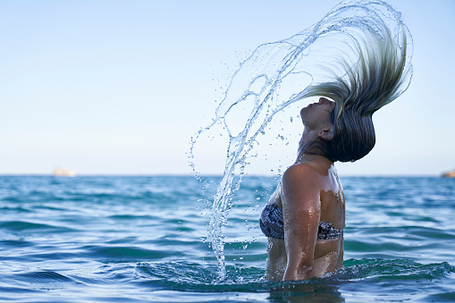 Woman throwing water in the sea with her hair.