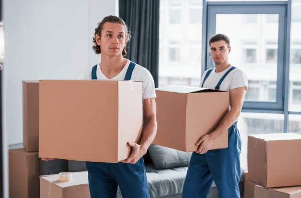 istock With boxes in hands. Two young movers in blue uniform working indoors in the room 1332291502