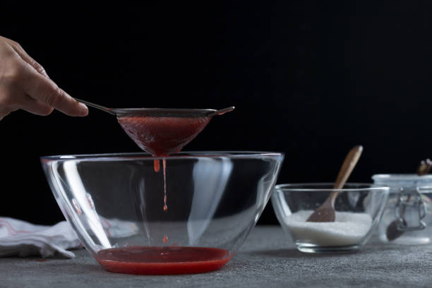 istock Woman straining strawberry jam through a sieve 1332291522