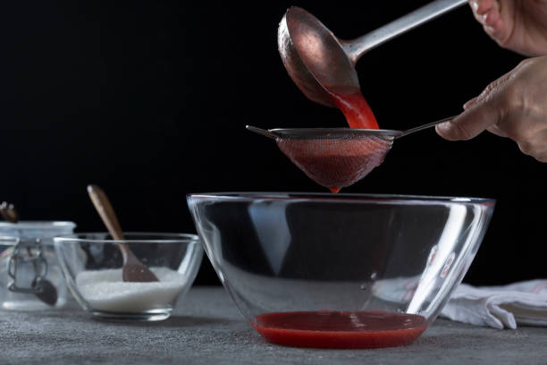 istock Woman straining strawberry jam through a sieve 1332291529