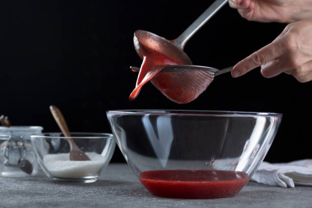 istock Woman straining strawberry jam through a sieve 1332291543