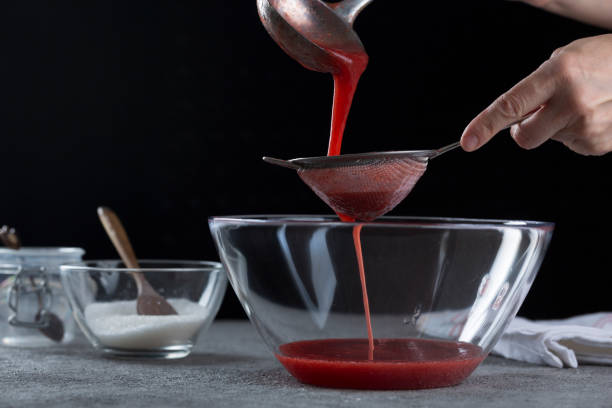 istock Woman straining strawberry jam through a sieve 1332291552