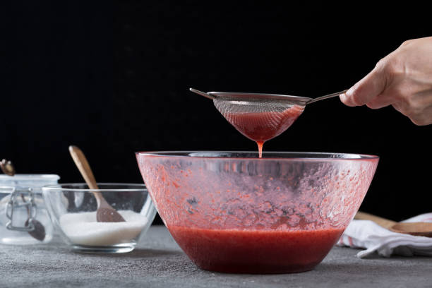 istock Woman straining strawberry jam through a sieve 1332291555