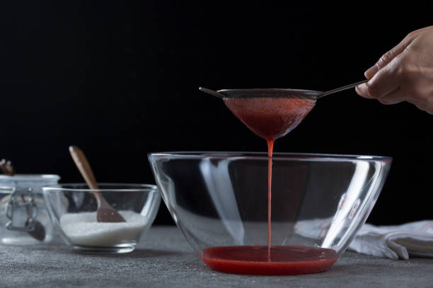 istock Woman straining strawberry jam through a sieve 1332291565