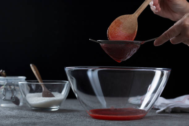 istock Woman straining strawberry jam through a sieve 1332291604