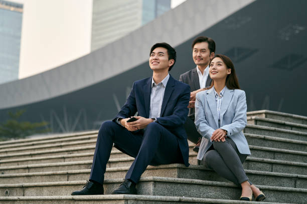 asian business people relaxing outdoors stock photo