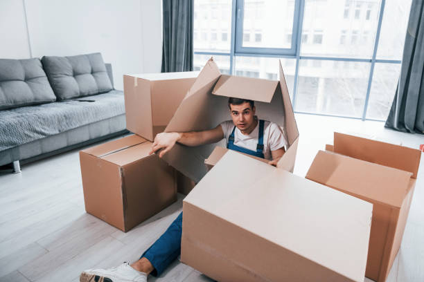 istock Young male mover in blue uniform lying down on the floor with boxes 1332295529