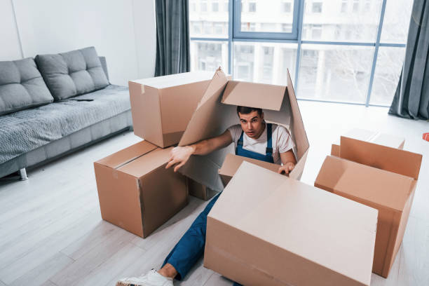 istock Young male mover in blue uniform lying down on the floor with boxes 1332295556
