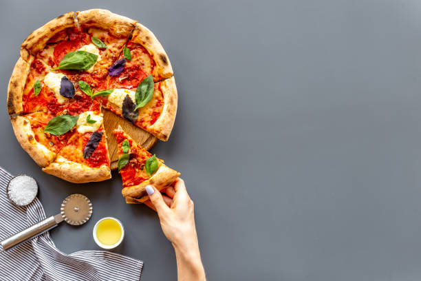 istock Female hands hold slice of pizza. Overhead view 1332298381