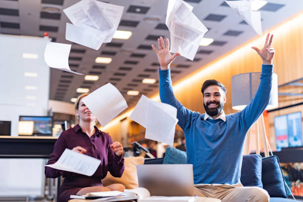 istock Happy business people throwing papers in office 1332301189