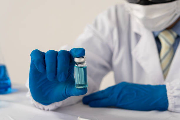 modern laboratory scientists conduct an experiment by synthesizing a compound in a bottle in hand. scientists are testing vaccines against covid-19. - checking the time imagens e fotografias de stock