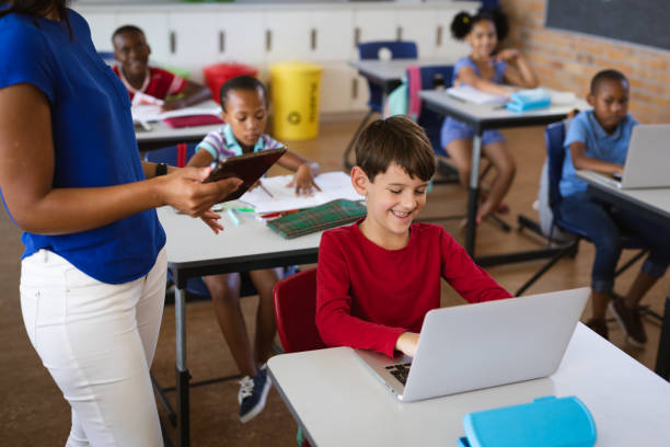 istock Mid section of female teacher teaching caucasian boy to use digital tablet at elementary school 1332306994