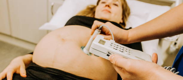 położna badanie brzucha leżącej kobiety w ciąży - położna sprawdza brzuch kobiety w ciąży z ctg praktyki skanowania - położna sprawdzanie serca płodu za pomocą kardiotokografu - położna sprawdzanie - fetus zdjęcia i obrazy z banku zdjęć