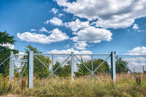blue metal fence gate with barb wire in a landscape
