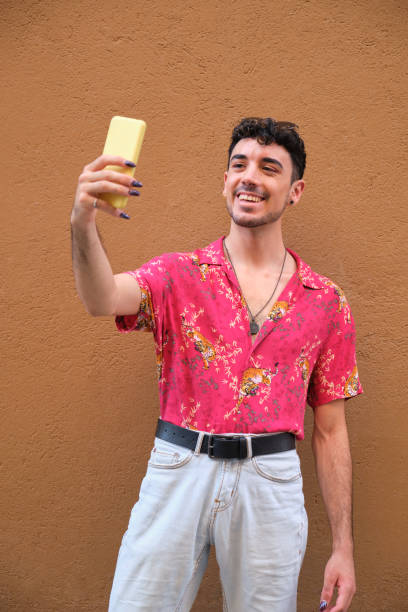 istock Young caucasian man with long false nails taking a selfie with his phone. 1332315059