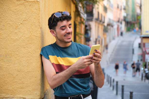 istock Young caucasian man with false nails using the phone standing against a wall. 1332315143