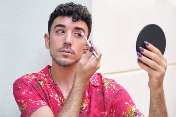 istock Young caucasian man with long false nails applying red eye shadow at street. 1332315199