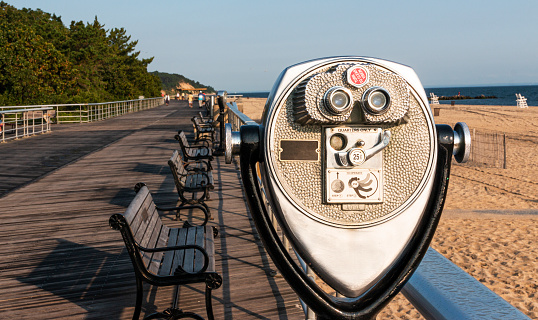 Looking west down the boardwalk at Sunken Meadow State Park with a stationary coin operated binoculars in the foreground.