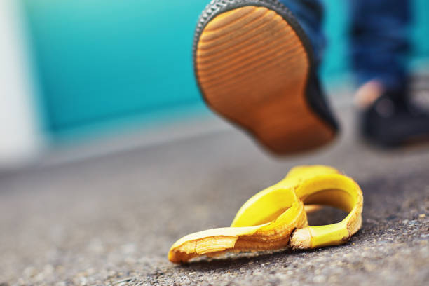 Accident about to happen! Foot approaches slippery banana skin Classic misfortune in the making as a walker's shoe is about to step on a banana peel. slippery unrecognizable person safety outdoors stock pictures, royalty-free photos & images