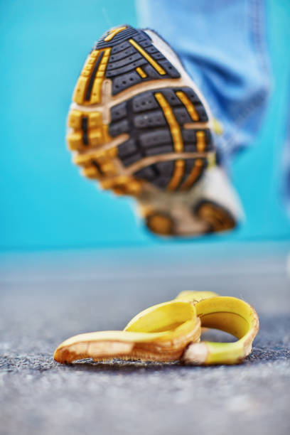 Accident about to happen! Foot approaches slippery banana skin Classic misfortune in the making as a walker's shoe is about to step on a banana peel. slippery unrecognizable person safety outdoors stock pictures, royalty-free photos & images