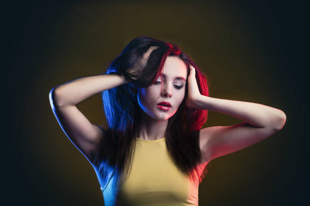 istock Young beautiful portrait model posing on yellow background in Studio in top, with blue and red backlight 1332316794